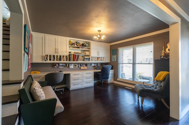 office area with dark wood-style floors, baseboards, built in desk, a textured ceiling, and a chandelier