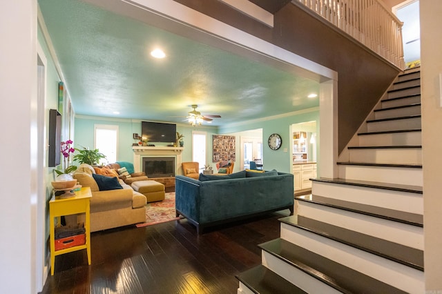 living room with stairs, dark wood-type flooring, plenty of natural light, and ceiling fan