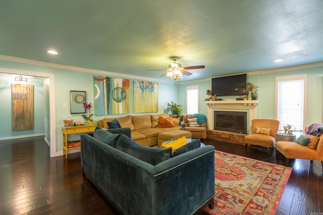 living room featuring a textured ceiling, a fireplace, dark wood-style flooring, and ornamental molding