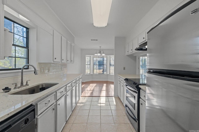 kitchen with a sink, backsplash, stainless steel appliances, white cabinets, and light tile patterned floors