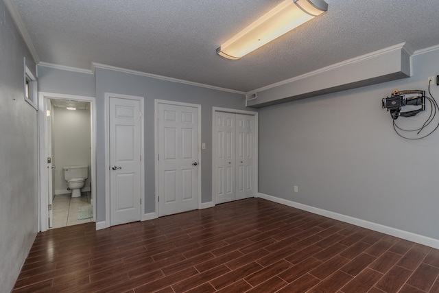 unfurnished bedroom with a textured ceiling, crown molding, baseboards, and dark wood-style flooring