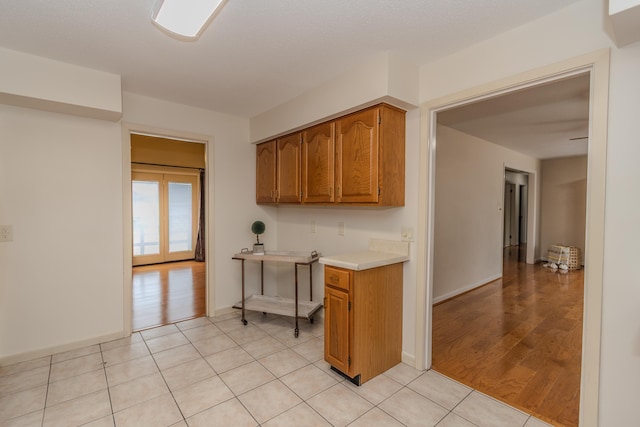 kitchen with light countertops, light tile patterned floors, brown cabinetry, and baseboards