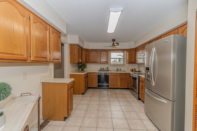 kitchen featuring a sink, stainless steel appliances, light tile patterned flooring, light countertops, and ceiling fan