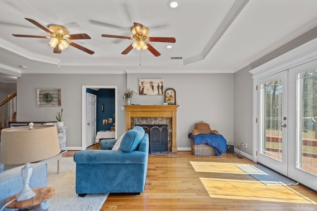 living room with visible vents, crown molding, a tray ceiling, wood finished floors, and a ceiling fan