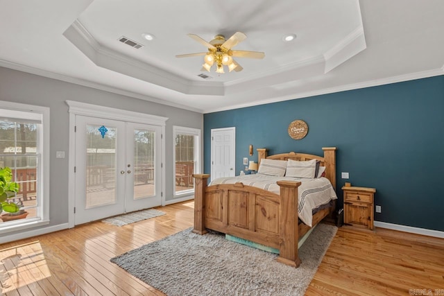 bedroom featuring a raised ceiling, multiple windows, access to exterior, and visible vents