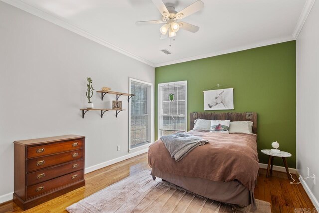 bedroom with baseboards, light wood-style floors, visible vents, and ornamental molding