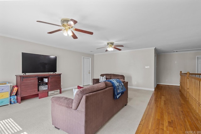 living area with ornamental molding, light wood-style floors, baseboards, attic access, and ceiling fan