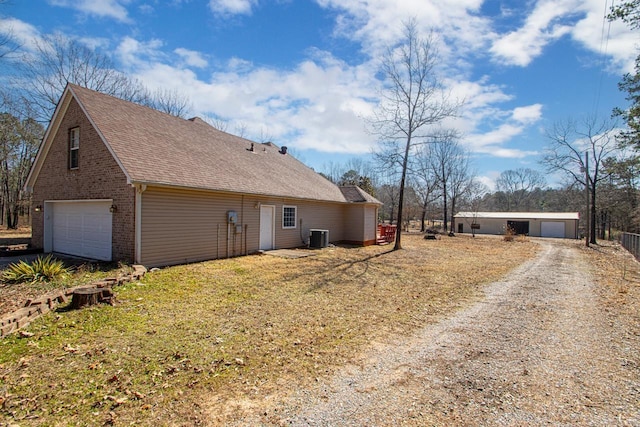 back of property with a garage, central air condition unit, brick siding, and a shingled roof