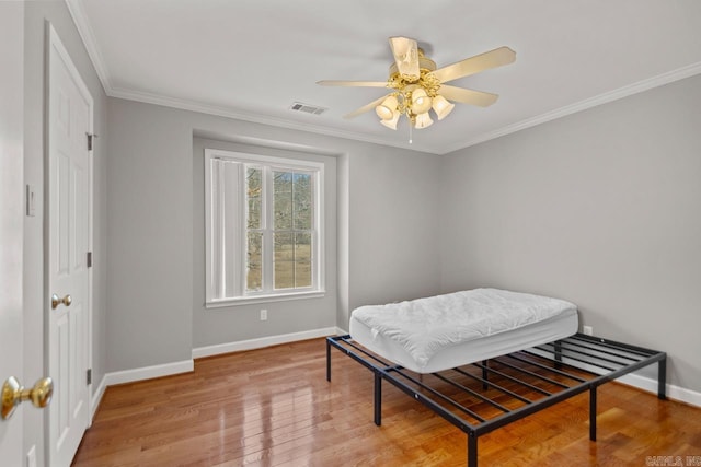 bedroom featuring visible vents, baseboards, ornamental molding, hardwood / wood-style floors, and a ceiling fan