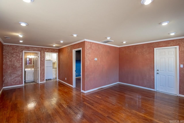 spare room featuring visible vents, crown molding, baseboards, and wood finished floors