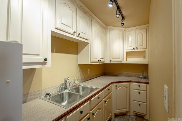 kitchen featuring light countertops, stone finish flooring, track lighting, and a sink