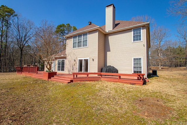 rear view of house featuring a deck, a yard, roof with shingles, and a chimney