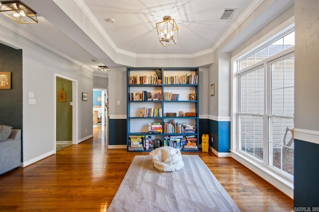 living area featuring a chandelier, visible vents, ornamental molding, and hardwood / wood-style flooring