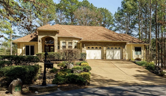 view of front facade with stone siding, stucco siding, driveway, and an attached garage