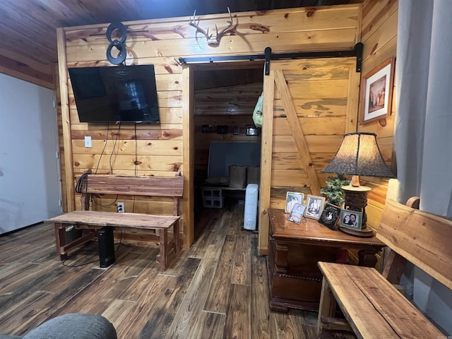 interior space with a barn door, wooden walls, and wood finished floors