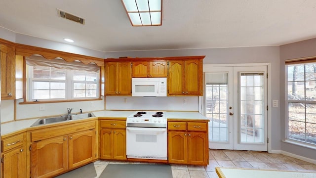 kitchen featuring visible vents, brown cabinets, a sink, white appliances, and light countertops