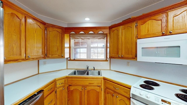 kitchen with a sink, white appliances, brown cabinetry, and light countertops