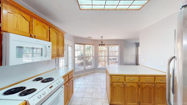 kitchen with a notable chandelier, white appliances, a peninsula, light countertops, and light tile patterned floors