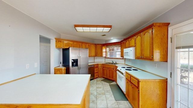 kitchen featuring appliances with stainless steel finishes, a healthy amount of sunlight, brown cabinetry, and light countertops