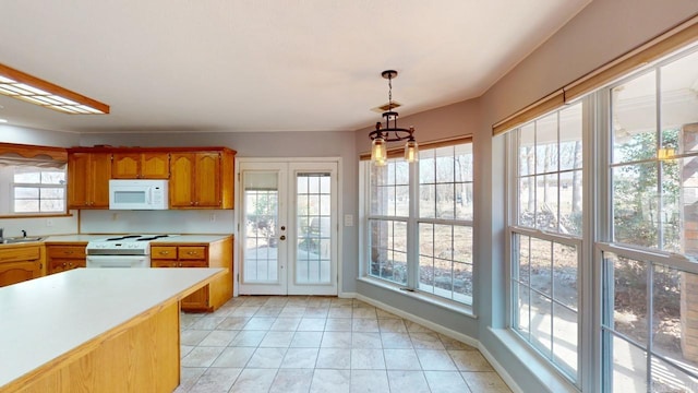 kitchen with brown cabinets, a sink, white appliances, light countertops, and hanging light fixtures