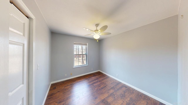 empty room with dark wood finished floors, baseboards, and a ceiling fan