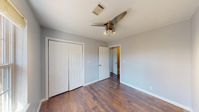 unfurnished bedroom featuring visible vents, ceiling fan, baseboards, dark wood finished floors, and a closet