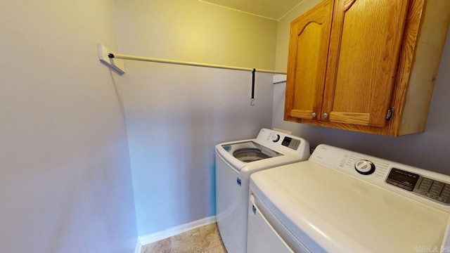 washroom featuring cabinet space, baseboards, and washer and clothes dryer