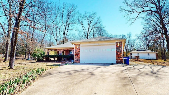 view of side of property with an attached garage, brick siding, and driveway