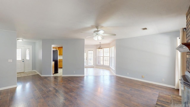 unfurnished living room with a wealth of natural light, hardwood / wood-style floors, a fireplace, and ceiling fan with notable chandelier