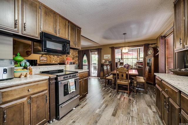 kitchen featuring light wood finished floors, pendant lighting, electric stove, and black microwave