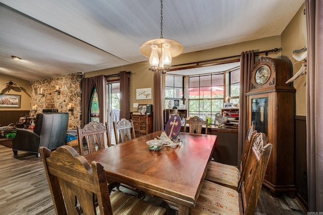 dining area with a notable chandelier, wood finished floors, and a textured ceiling