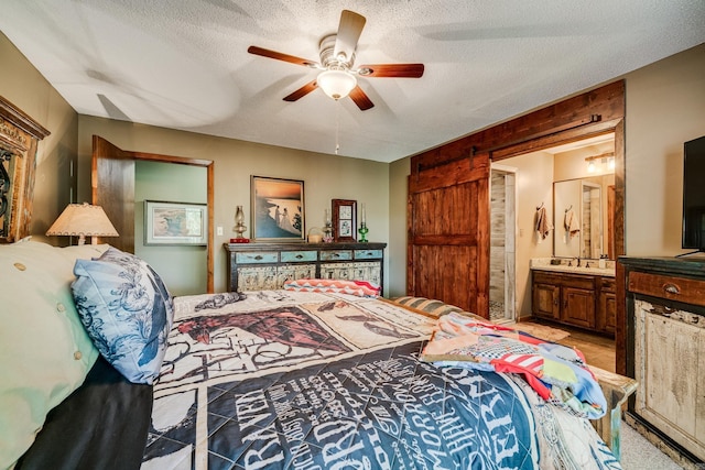 bedroom with a textured ceiling, ensuite bathroom, and a ceiling fan