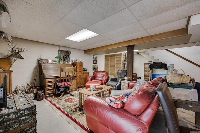 finished below grade area featuring concrete block wall and a paneled ceiling