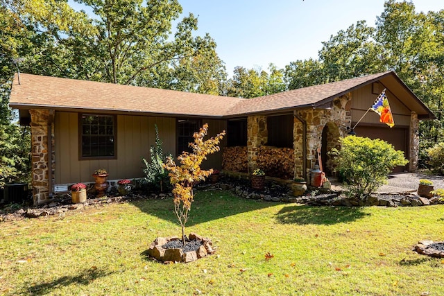 ranch-style home with stone siding, an attached garage, central AC, and a front yard