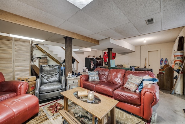 living room featuring visible vents, stairs, concrete flooring, and a paneled ceiling