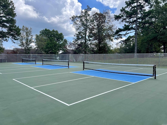 view of tennis court featuring community basketball court and fence