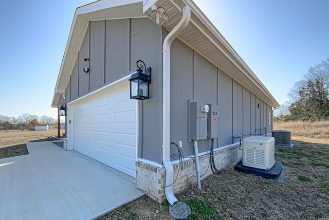 view of home's exterior with central AC unit, board and batten siding, driveway, and a garage