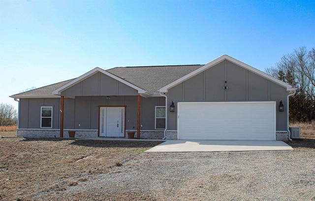 view of front facade with an attached garage, brick siding, dirt driveway, and roof with shingles