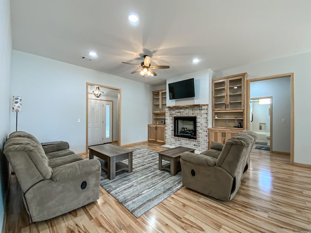 living area featuring visible vents, baseboards, light wood-style floors, and ceiling fan