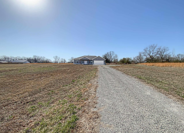 view of road with gravel driveway and a rural view