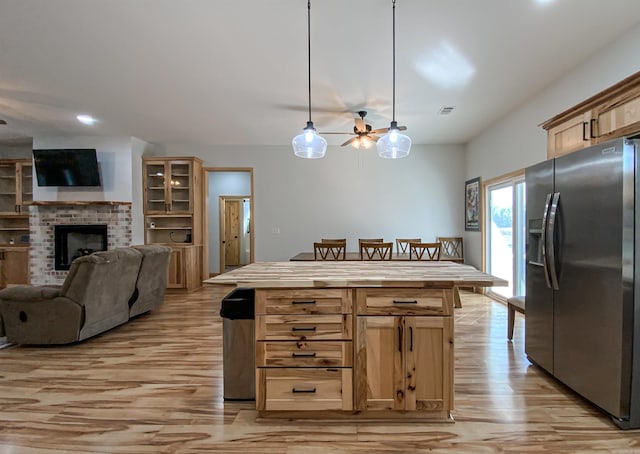 kitchen with a fireplace, stainless steel fridge with ice dispenser, light brown cabinetry, ceiling fan, and open floor plan