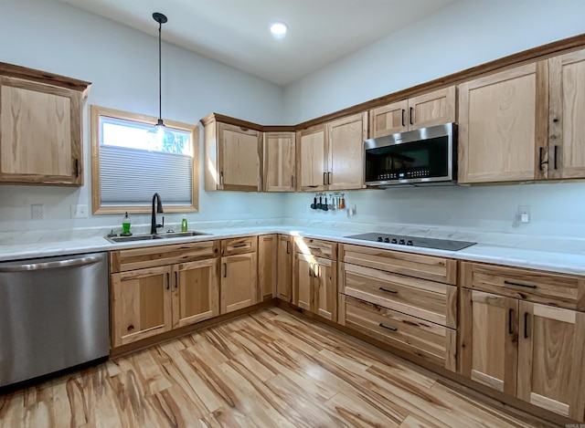 kitchen featuring light wood-type flooring, light brown cabinetry, a sink, stainless steel appliances, and light countertops