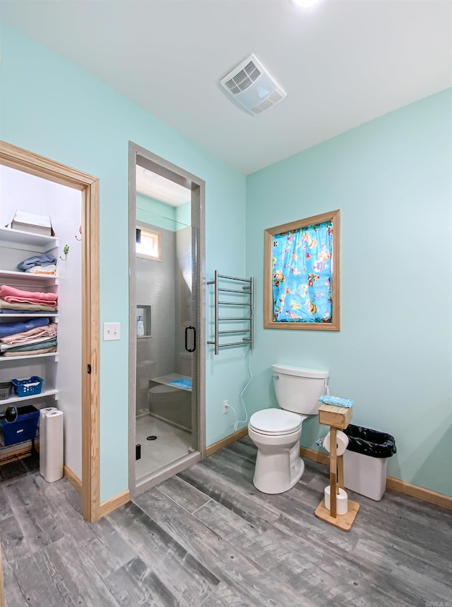 full bath featuring wood finished floors, visible vents, baseboards, a shower stall, and toilet