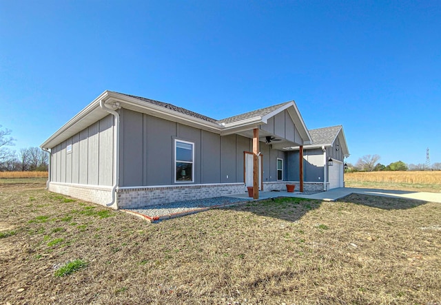 exterior space with brick siding, an attached garage, a yard, and board and batten siding