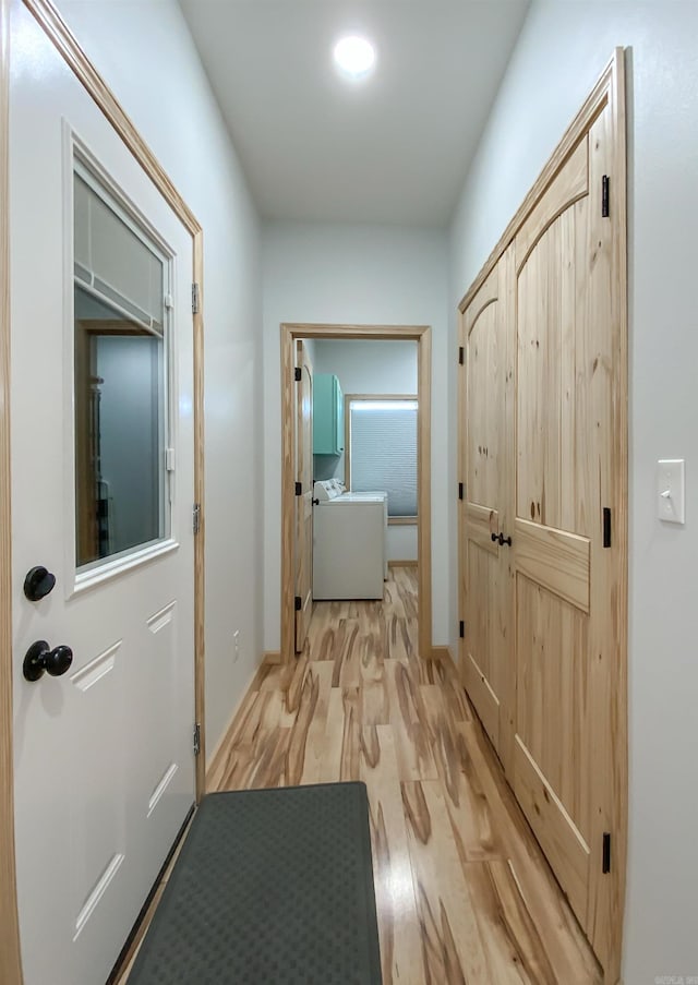 hallway with baseboards, washer / dryer, and light wood-style flooring