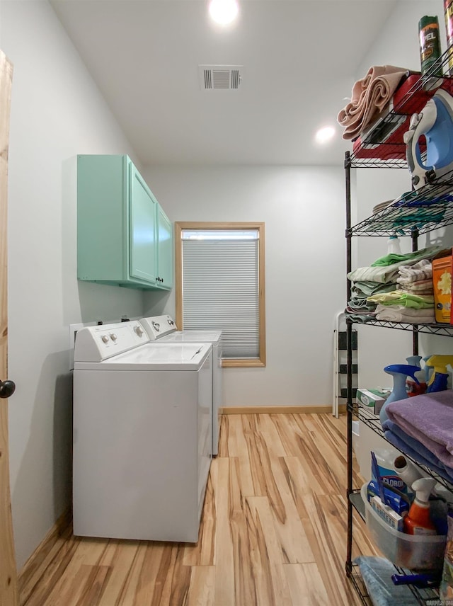 washroom with light wood-type flooring, visible vents, cabinet space, and independent washer and dryer