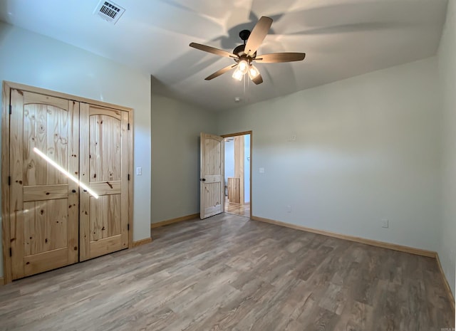 unfurnished bedroom with visible vents, a ceiling fan, baseboards, and wood finished floors