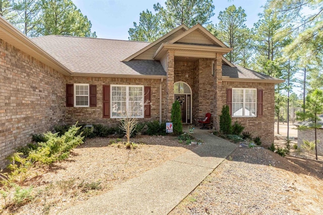 view of front facade featuring brick siding and a shingled roof