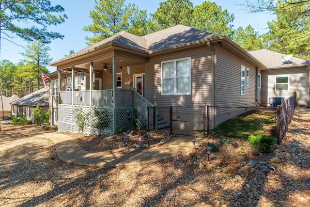 view of front of home featuring cooling unit, a ceiling fan, fence, covered porch, and a shingled roof