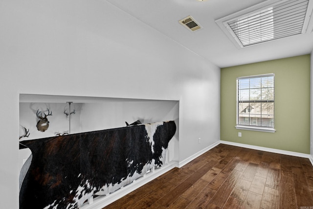 spare room with wood finished floors, visible vents, and baseboards